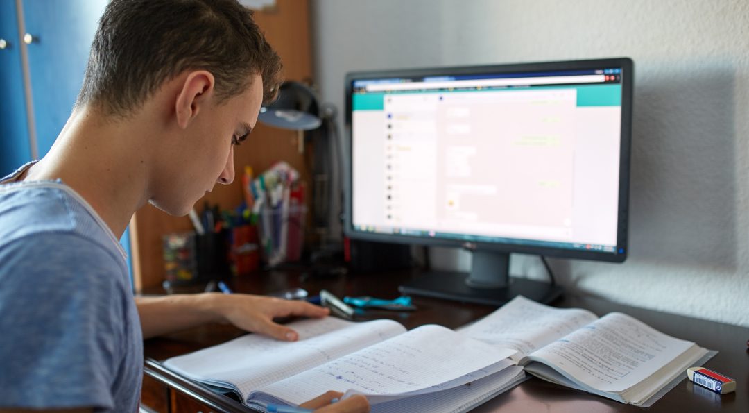 Teenager boy doing homework on his desk at home